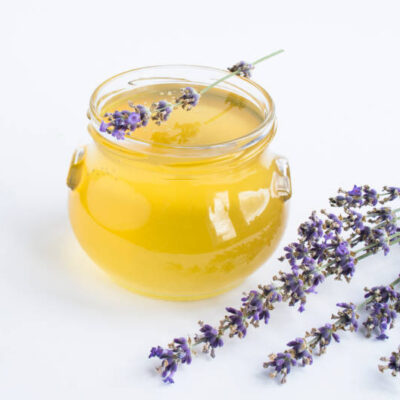 Honey in the glass jar and lavender flower on the white background. close up.