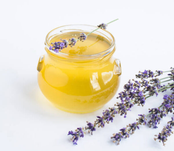 Honey in the glass jar and lavender flower on the white background. close up.
