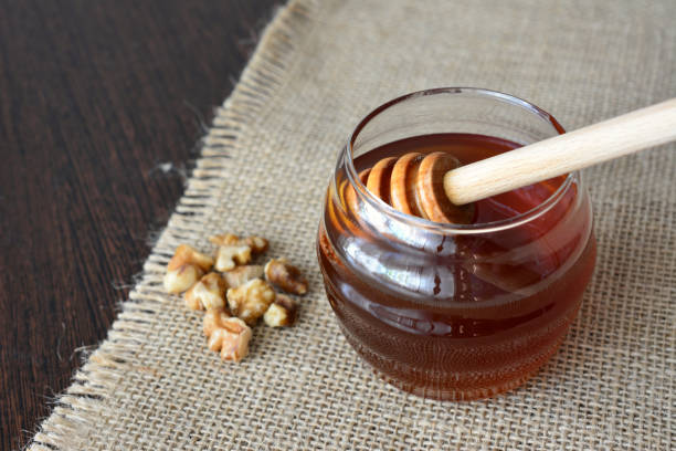Honey in a glass jar with walnuts on a burlap cloth