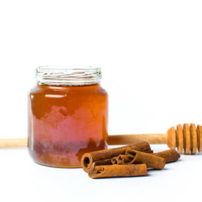Jar of honey and cinnamon isolated on white