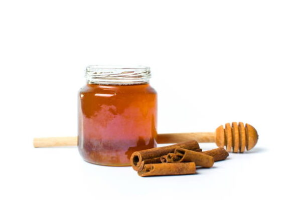 Jar of honey and cinnamon isolated on white