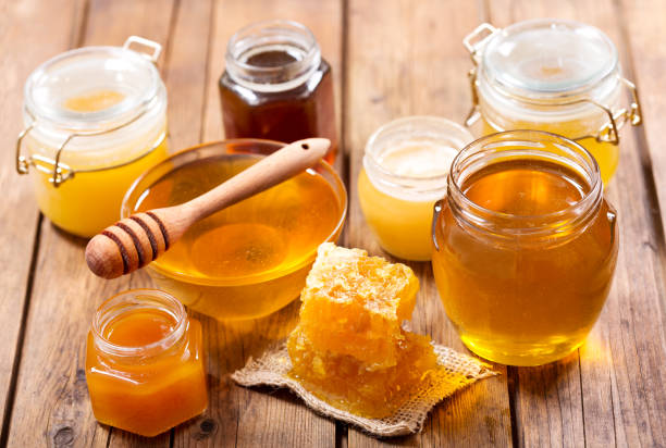 Various types of honey in glass jars on a wooden table