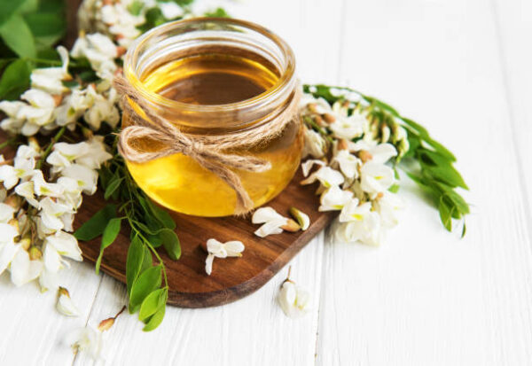 Honey with acacia blossoms on a wooden background